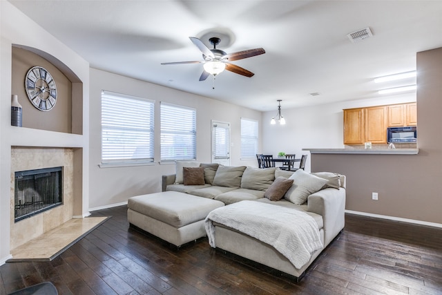 living room with a fireplace, dark hardwood / wood-style floors, and ceiling fan