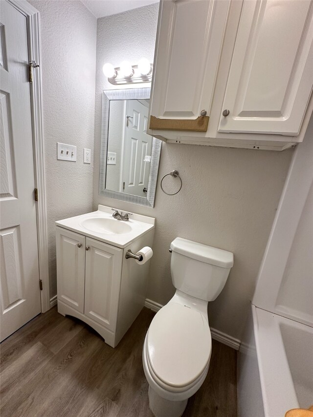 bathroom with vanity, toilet, and hardwood / wood-style flooring