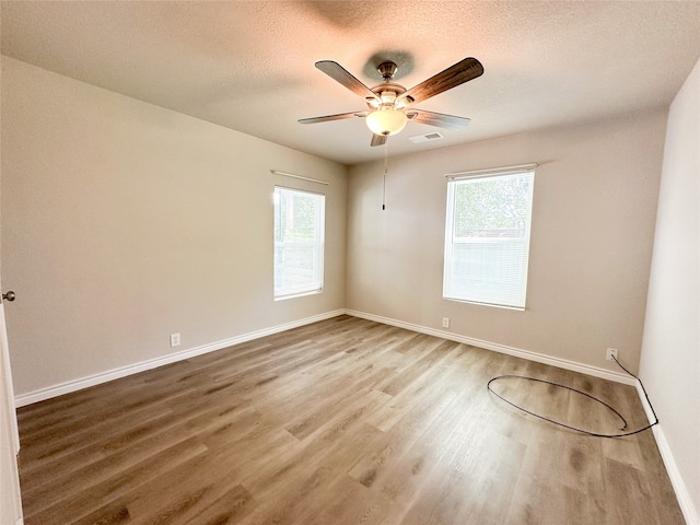 empty room featuring wood-type flooring, ceiling fan, and plenty of natural light