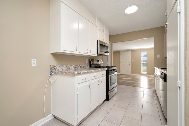 kitchen featuring a textured ceiling, light wood-type flooring, stainless steel appliances, and white cabinets