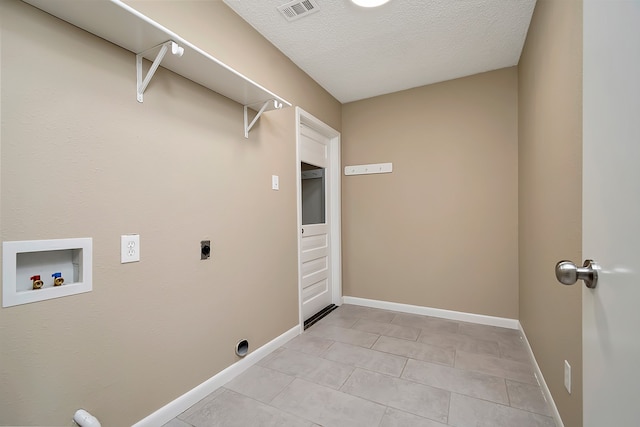 laundry room with hookup for a washing machine, a textured ceiling, light tile patterned flooring, and hookup for an electric dryer