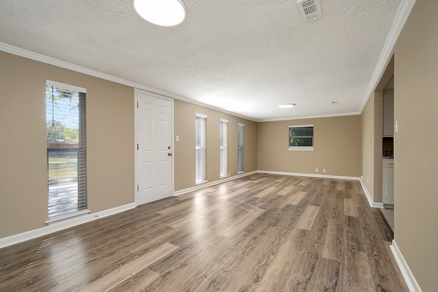 empty room with a textured ceiling, light hardwood / wood-style flooring, and ornamental molding