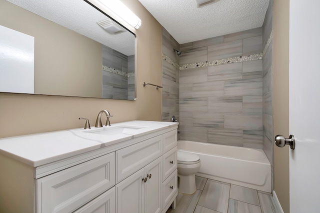 full bathroom featuring a textured ceiling, tiled shower / bath, vanity, and toilet