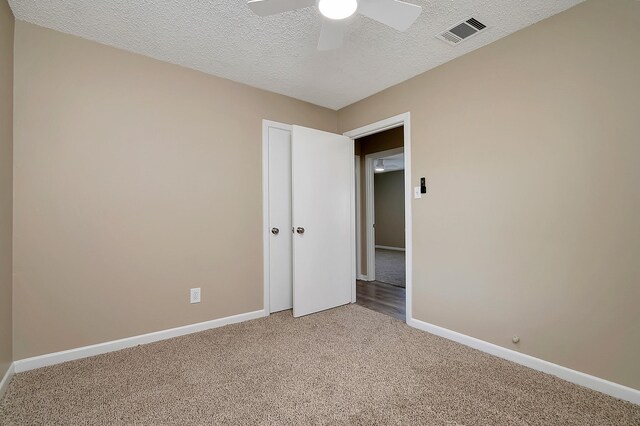 carpeted empty room with a textured ceiling and ceiling fan