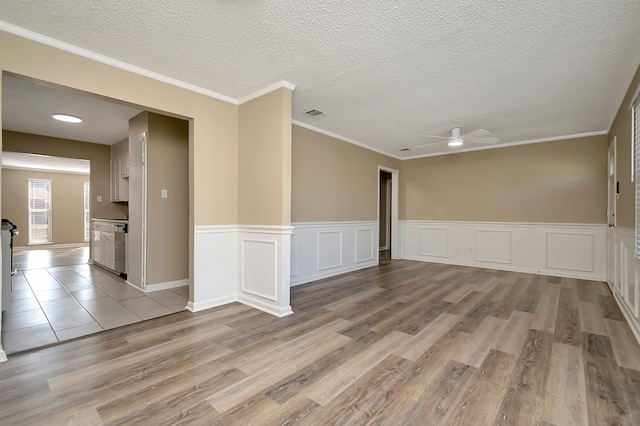 spare room featuring a textured ceiling, crown molding, light hardwood / wood-style floors, and ceiling fan