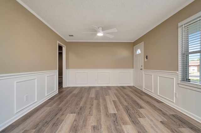 spare room featuring a textured ceiling, ornamental molding, ceiling fan, and light hardwood / wood-style flooring