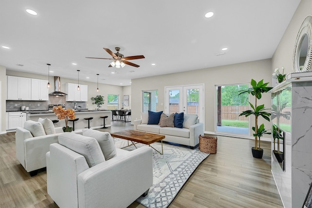 living room featuring light hardwood / wood-style floors, ceiling fan, and sink