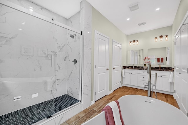 bathroom featuring hardwood / wood-style flooring, vanity, and plus walk in shower