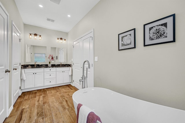 bathroom featuring hardwood / wood-style floors, a washtub, and vanity