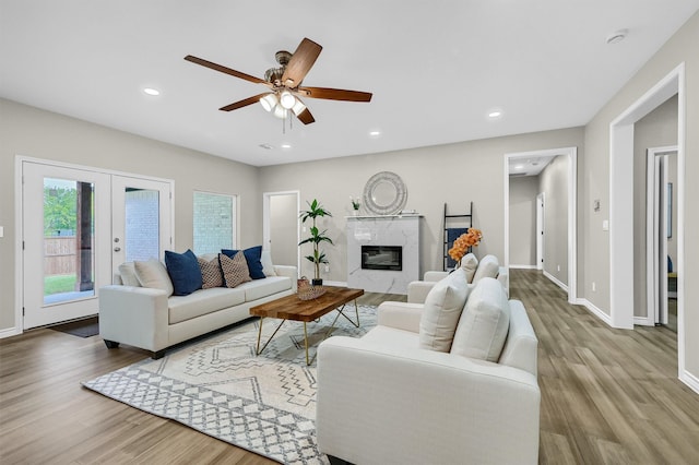 living room featuring a premium fireplace, light hardwood / wood-style flooring, and ceiling fan