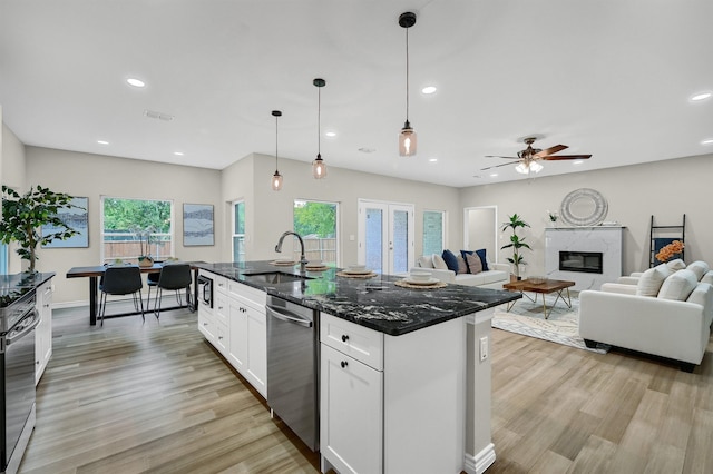 kitchen with dark stone counters, a wealth of natural light, sink, and dishwasher