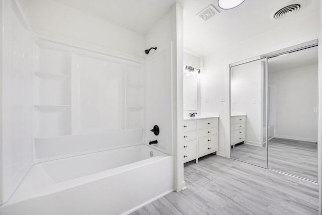 bathroom featuring wood-type flooring, shower / bath combination, and vanity