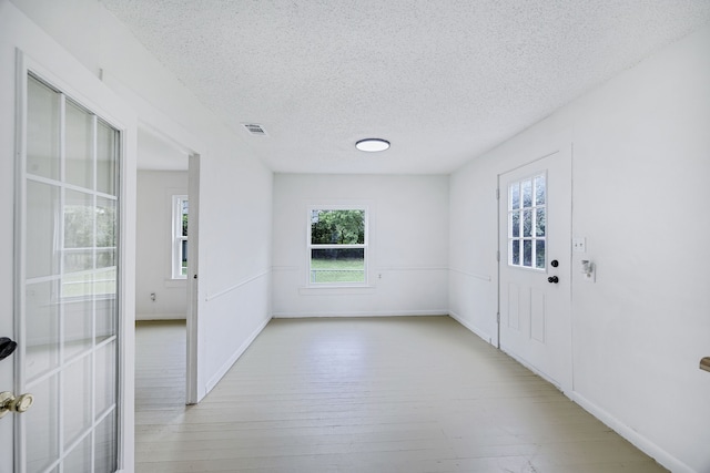 unfurnished room with a textured ceiling and light hardwood / wood-style floors