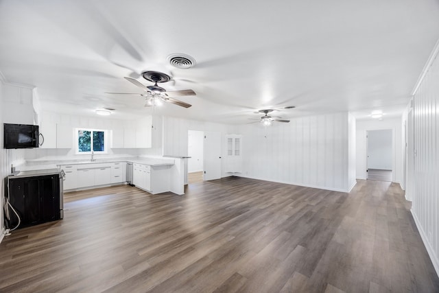 unfurnished living room featuring wood-type flooring, ceiling fan, and sink