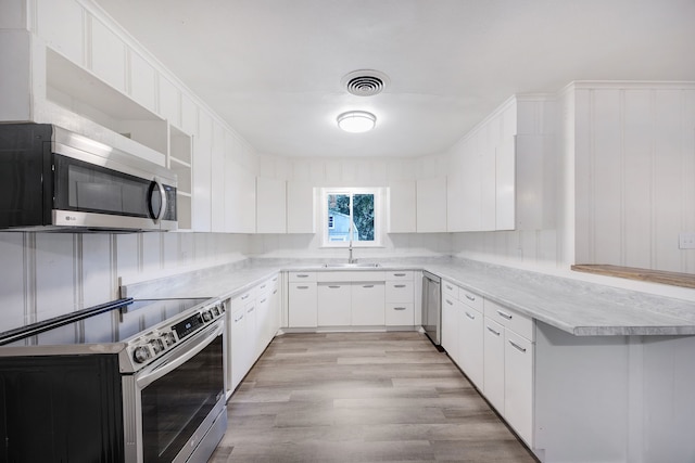 kitchen featuring sink, white cabinetry, kitchen peninsula, light hardwood / wood-style flooring, and stainless steel appliances