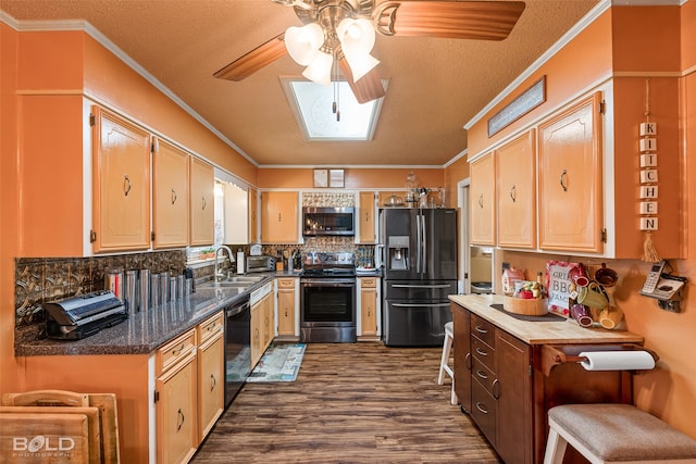 kitchen featuring ceiling fan, a skylight, ornamental molding, appliances with stainless steel finishes, and dark hardwood / wood-style floors