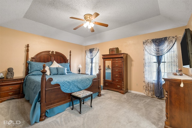 bedroom featuring a raised ceiling, ceiling fan, and light colored carpet