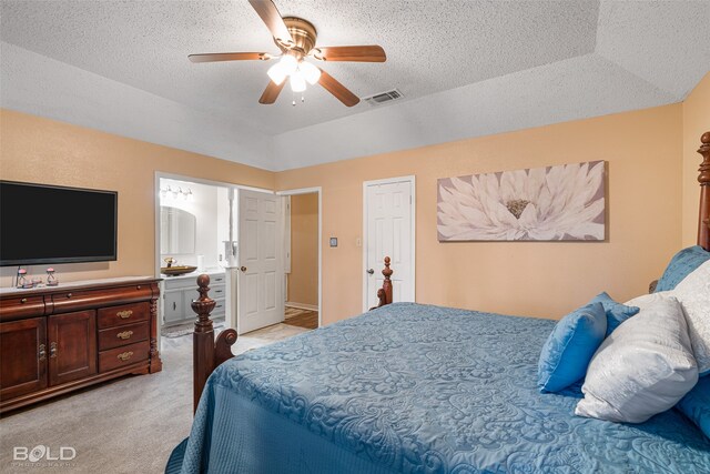 bedroom featuring light carpet, ensuite bath, ceiling fan, and a textured ceiling