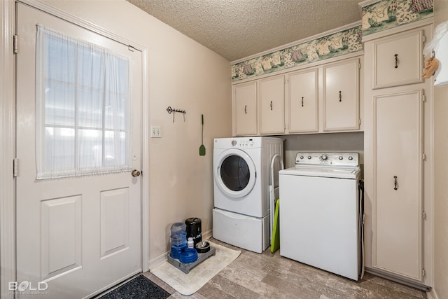 laundry room with cabinets, a textured ceiling, light hardwood / wood-style flooring, and washing machine and dryer