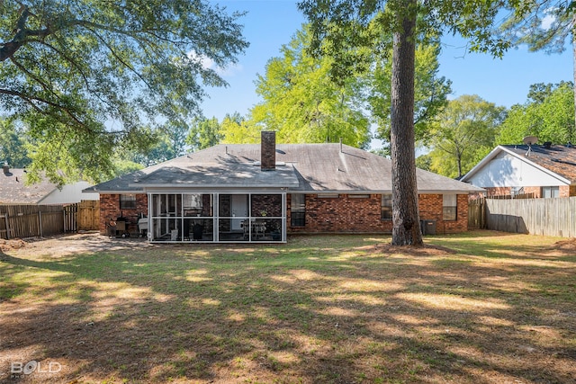 rear view of house with cooling unit, a sunroom, and a lawn