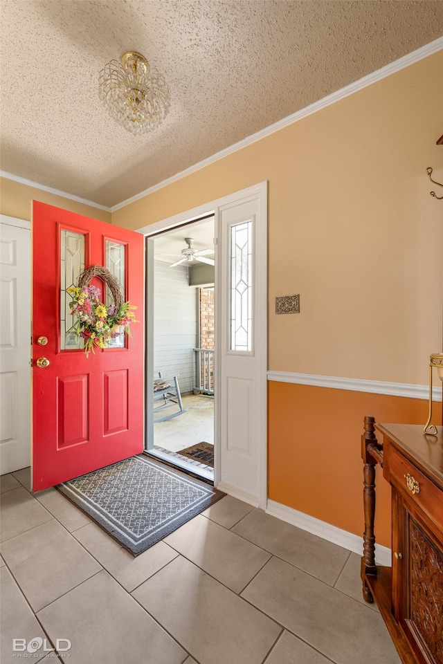 tiled foyer featuring ceiling fan, crown molding, and a textured ceiling