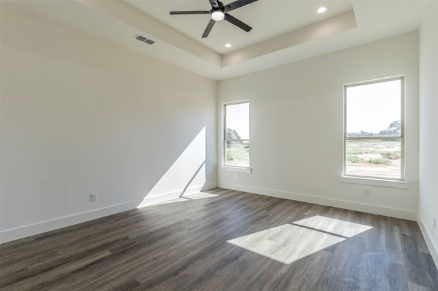 spare room featuring a tray ceiling, ceiling fan, and dark wood-type flooring