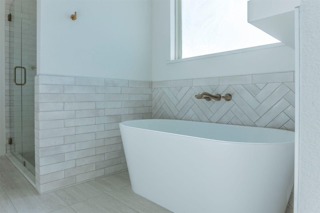 bathroom featuring tile patterned flooring, tile walls, and independent shower and bath