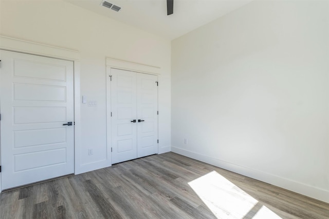 unfurnished bedroom with ceiling fan, a closet, and wood-type flooring