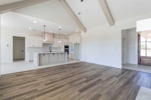 unfurnished living room with hardwood / wood-style floors, high vaulted ceiling, beamed ceiling, and sink