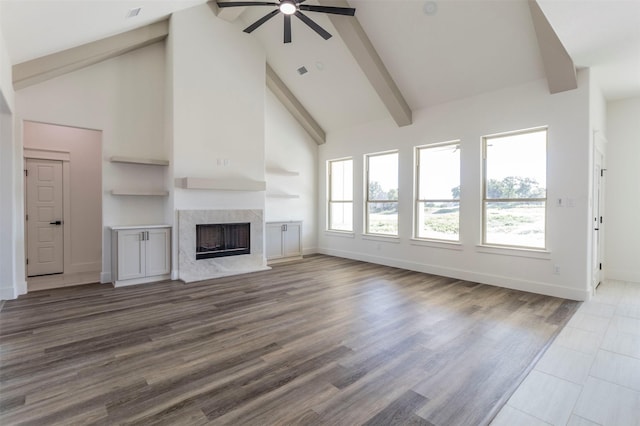 unfurnished living room with a high end fireplace, hardwood / wood-style floors, high vaulted ceiling, and beam ceiling