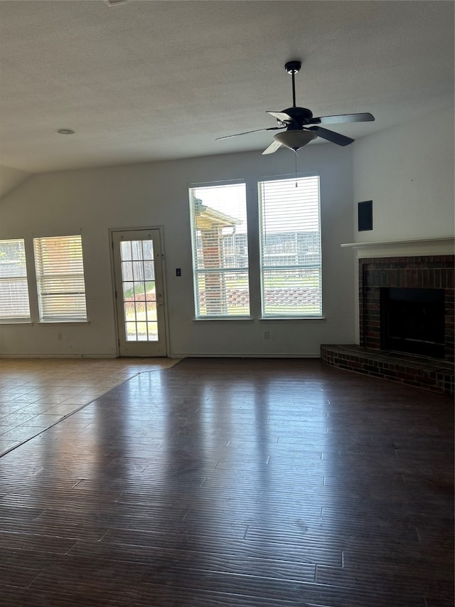 unfurnished living room featuring ceiling fan, a brick fireplace, a textured ceiling, vaulted ceiling, and dark hardwood / wood-style flooring