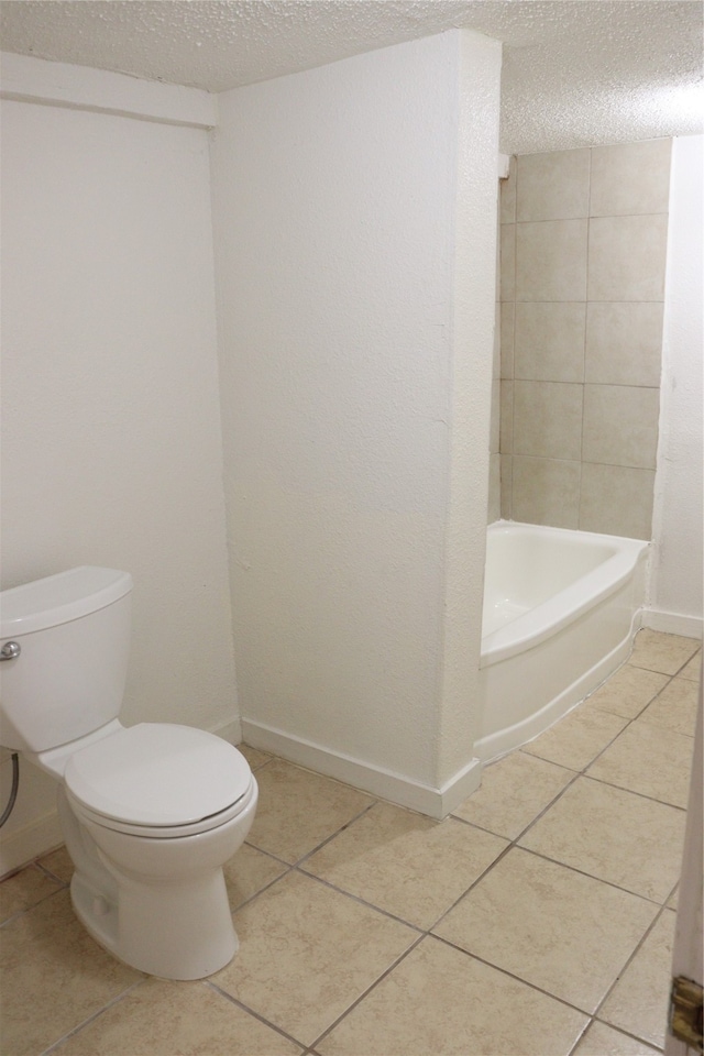 bathroom with tile patterned flooring, a textured ceiling, a washtub, and toilet