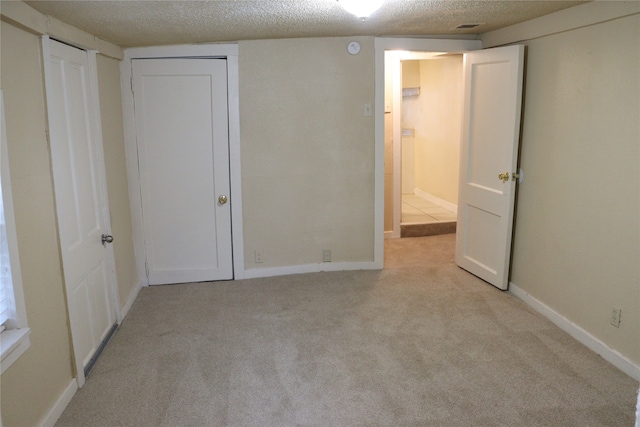 unfurnished bedroom with a textured ceiling and light colored carpet