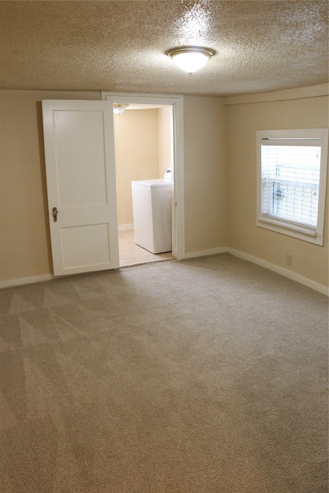 carpeted empty room featuring a textured ceiling and washer / dryer