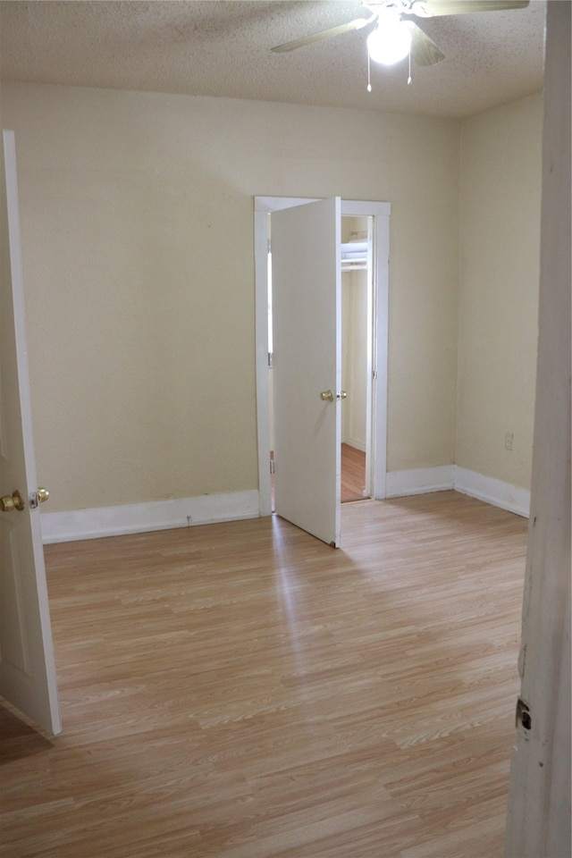 unfurnished room featuring light hardwood / wood-style flooring, ceiling fan, and a textured ceiling