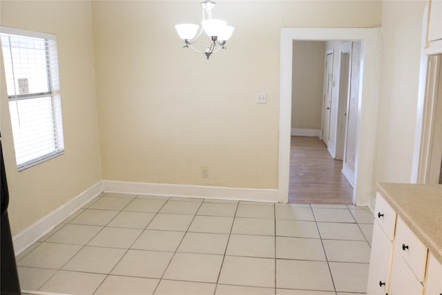 unfurnished dining area featuring an inviting chandelier and light tile patterned floors