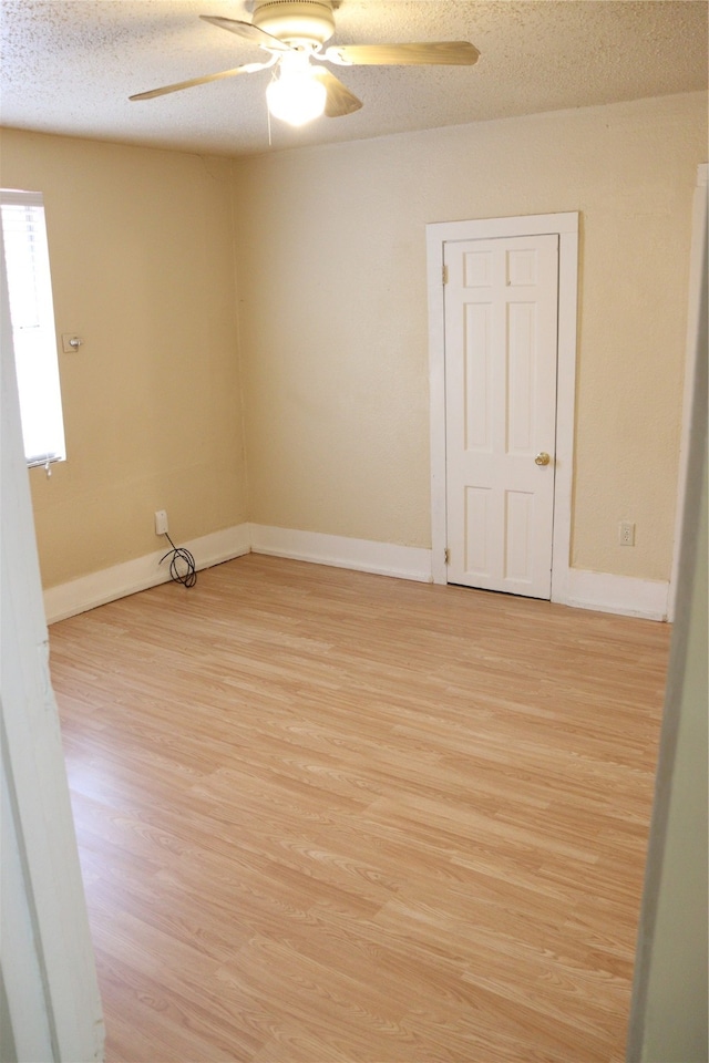 spare room with light wood-type flooring, ceiling fan, and a textured ceiling