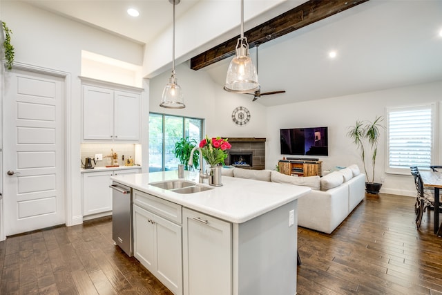 kitchen with a kitchen island with sink, a fireplace, hanging light fixtures, and white cabinetry