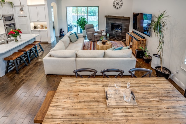 living room with a fireplace and dark wood-type flooring