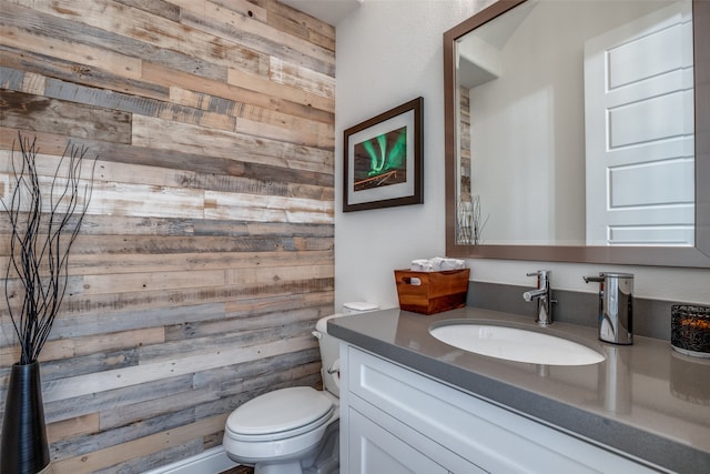 bathroom featuring wooden walls, vanity, and toilet