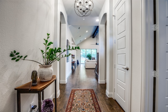 hallway with a notable chandelier, dark wood-type flooring, and vaulted ceiling