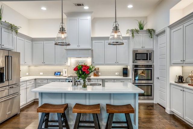 kitchen with pendant lighting, appliances with stainless steel finishes, dark wood-type flooring, and decorative backsplash