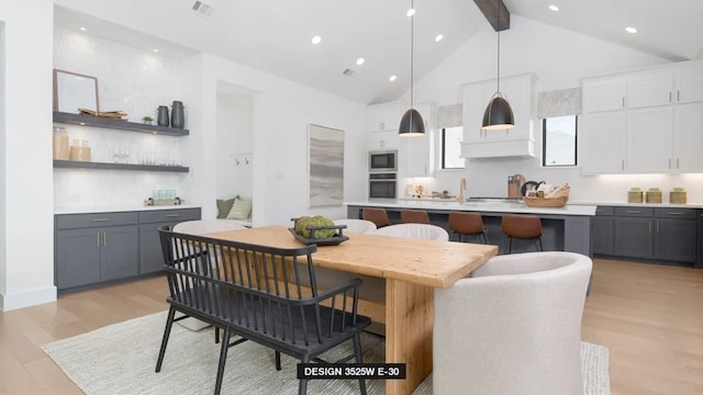 dining area featuring high vaulted ceiling, beam ceiling, light hardwood / wood-style floors, and sink