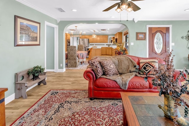 living room with ornamental molding, light hardwood / wood-style floors, and ceiling fan