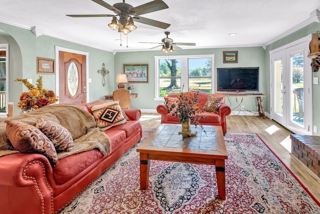 living room with crown molding, light hardwood / wood-style floors, ceiling fan, and french doors