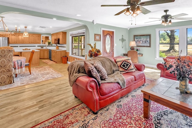 living room featuring ceiling fan with notable chandelier, light hardwood / wood-style flooring, and crown molding