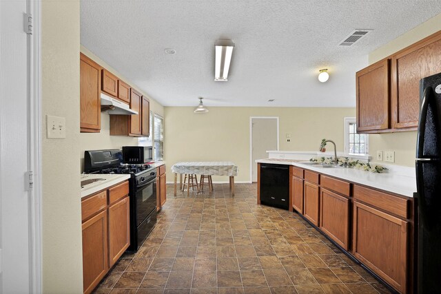 kitchen with a textured ceiling, black appliances, and sink