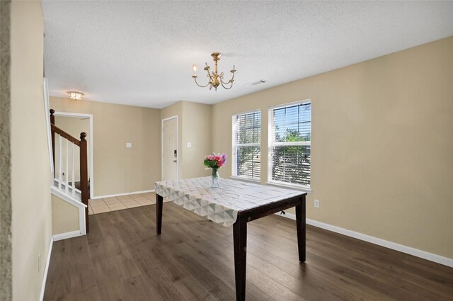 dining area with an inviting chandelier, a textured ceiling, and dark hardwood / wood-style floors