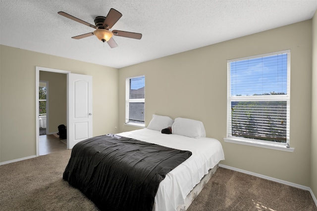 carpeted bedroom featuring ceiling fan, a textured ceiling, and multiple windows