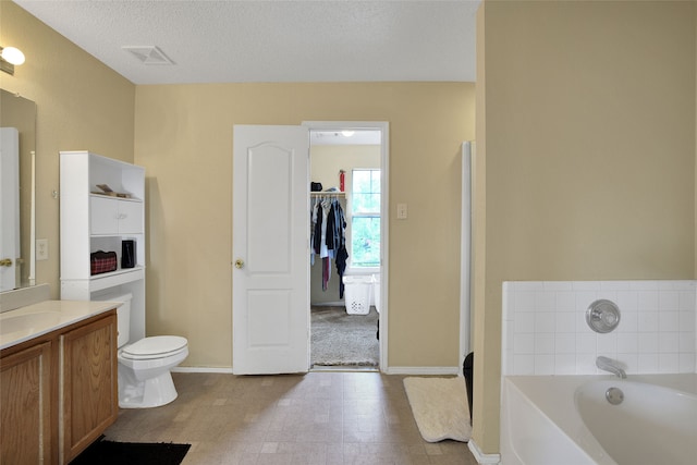 bathroom with a textured ceiling, a bath, vanity, and toilet